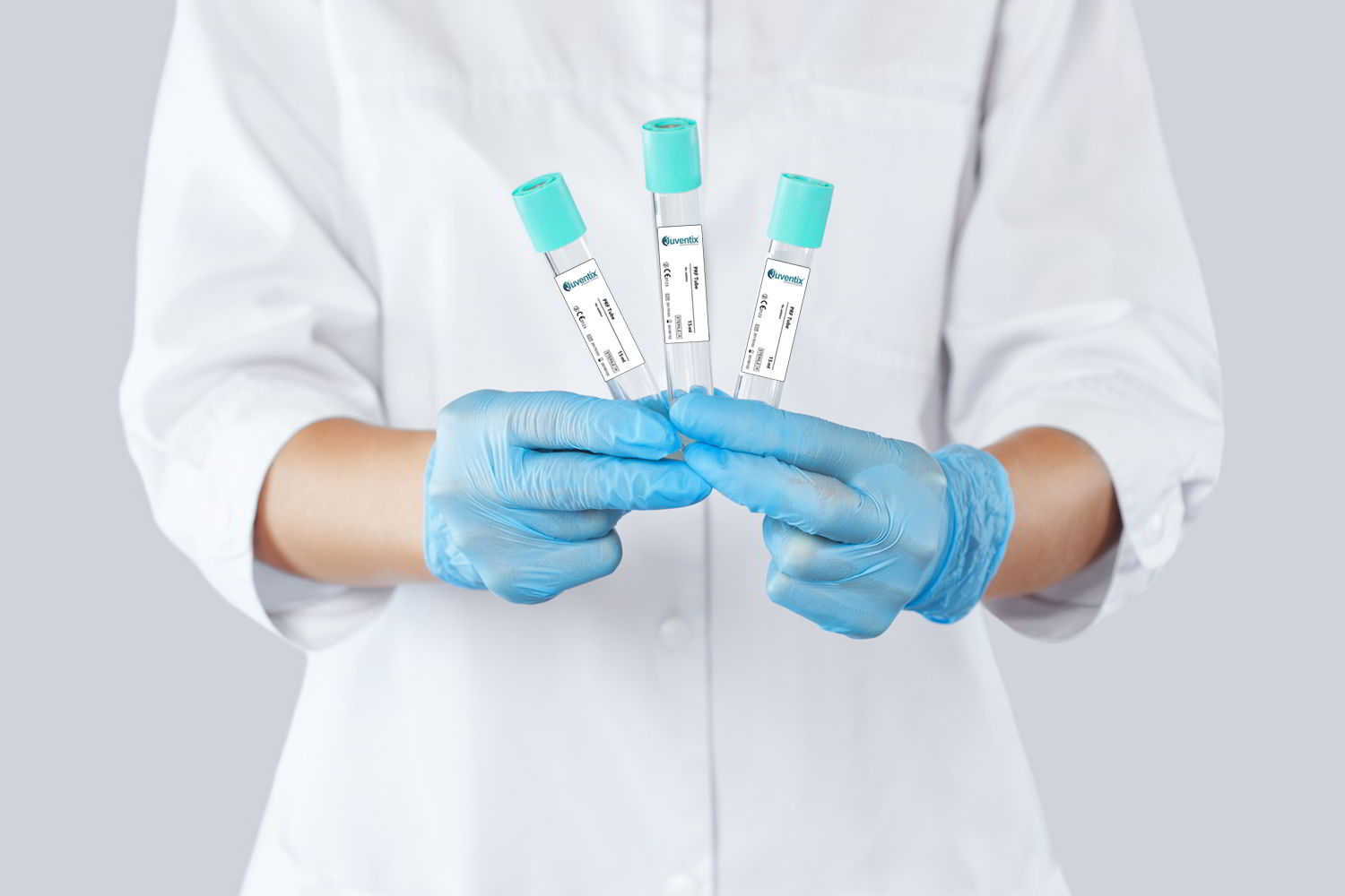 person in a white coat and blue gloves holding four medical tubes